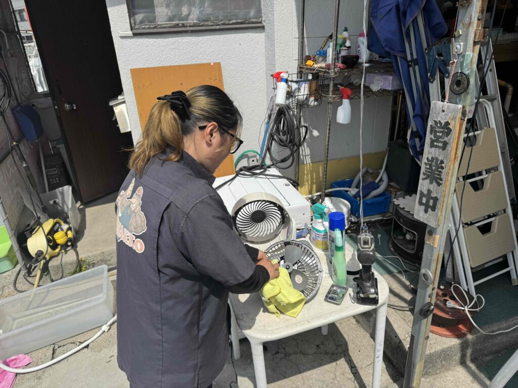 鹿児島市のリサイクルショップ八光で、スタッフが中古扇風機を丁寧に分解洗浄している様子