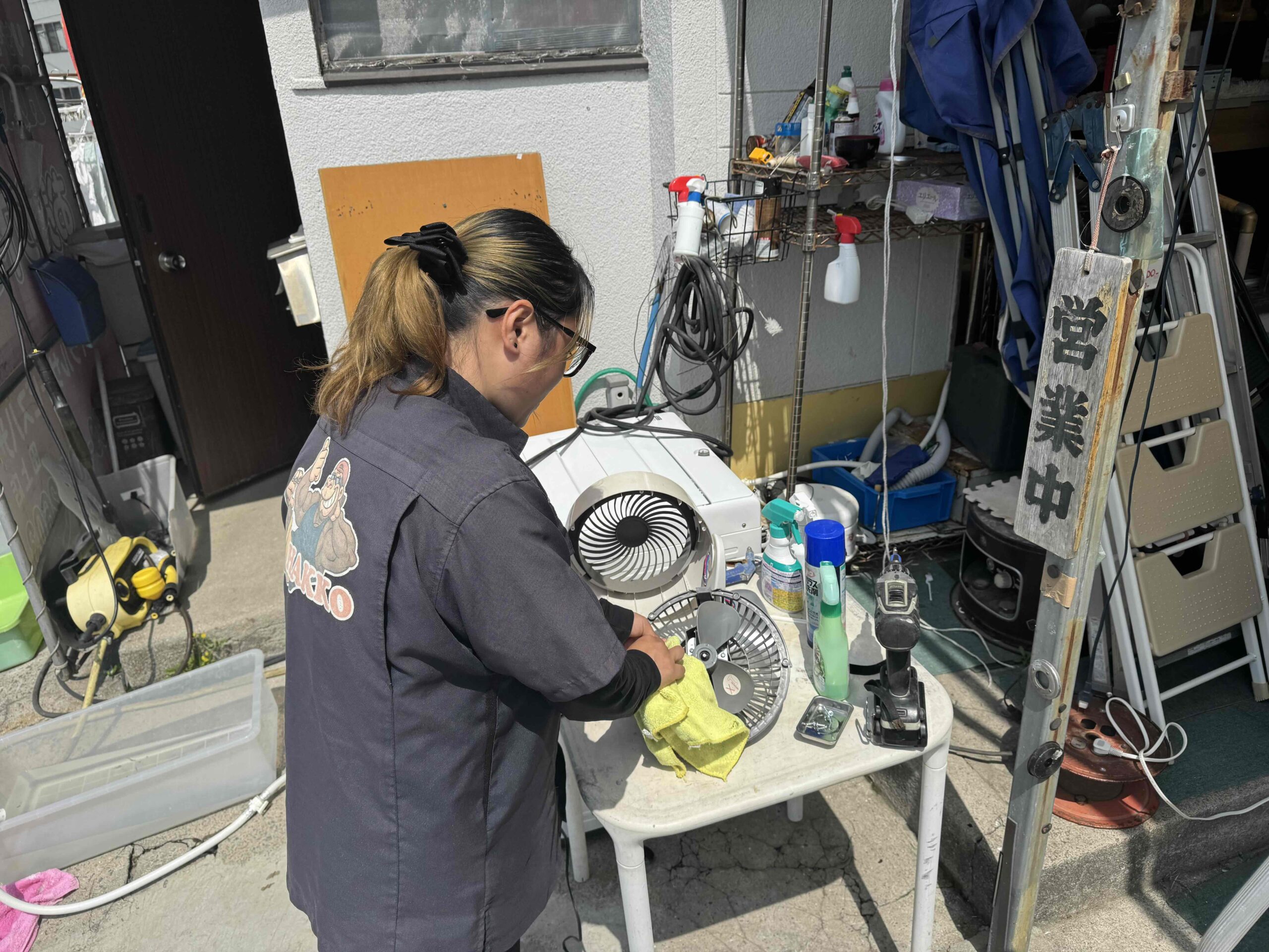 鹿児島市のリサイクルショップ八光で、スタッフが中古扇風機を丁寧に分解洗浄している様子