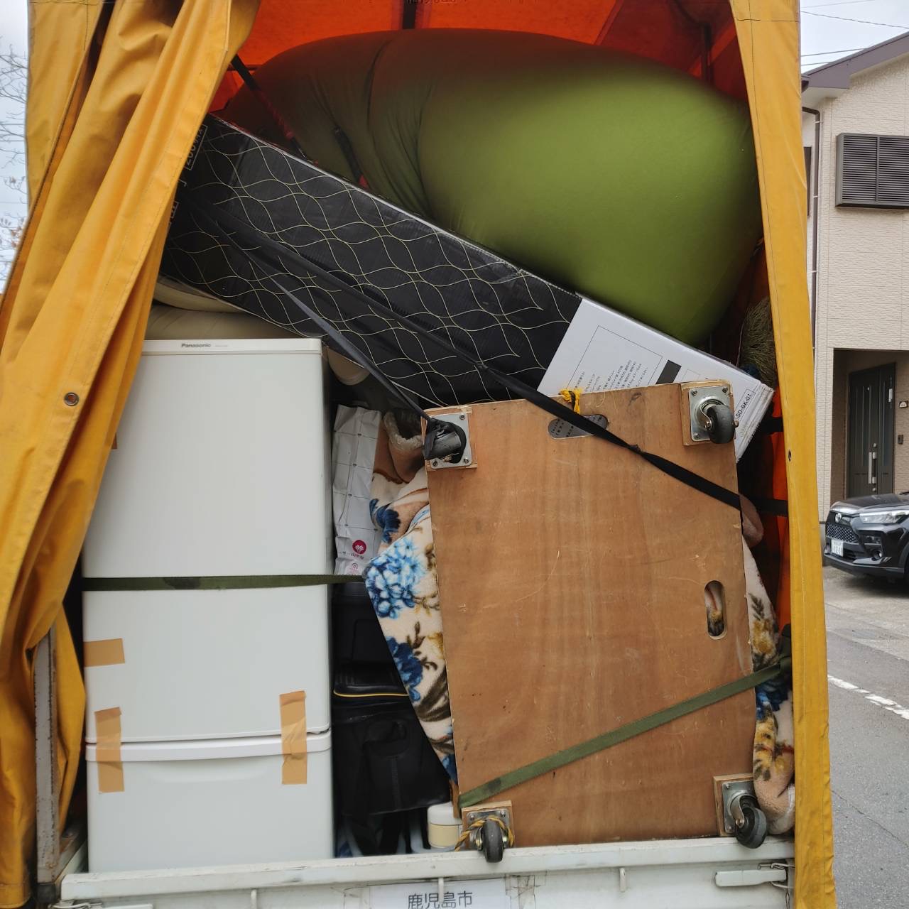 鹿児島市からの単身引越し作業で、幌付きトラックにしっかりと固定された冷蔵庫や大型家具