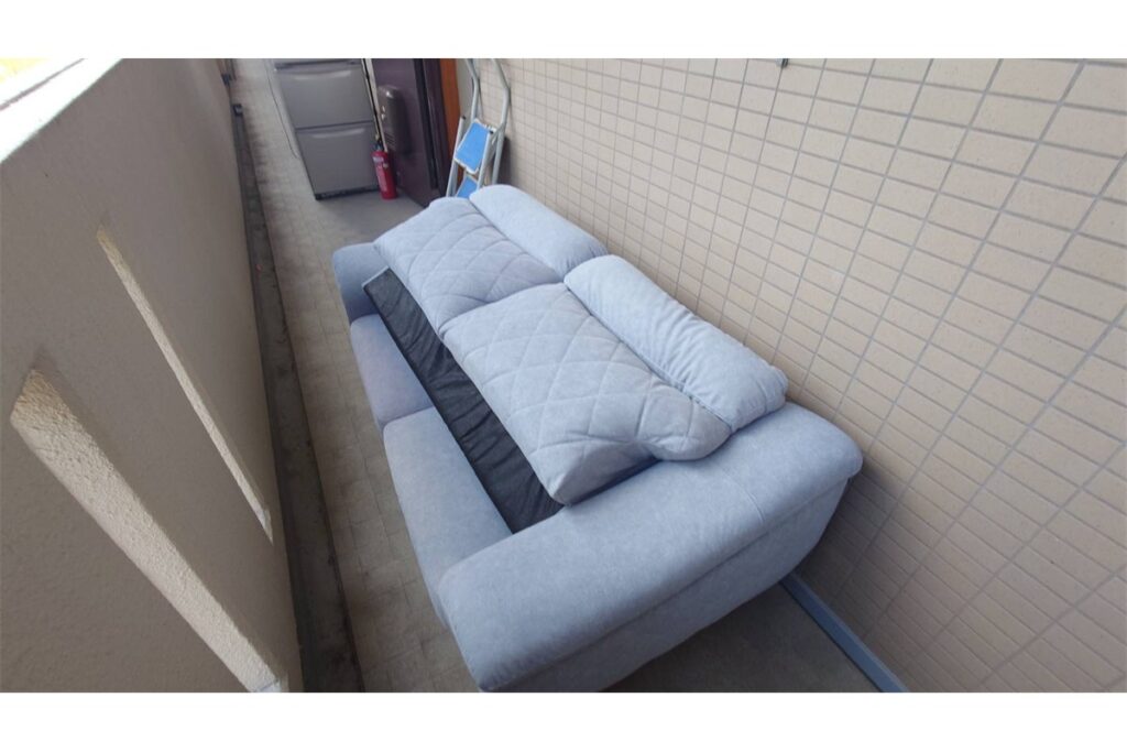 3人掛けグレーのソファをマンションのベランダに出した状態